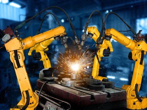 Gelbe Roboterarme führen eine Schweißarbeit aus