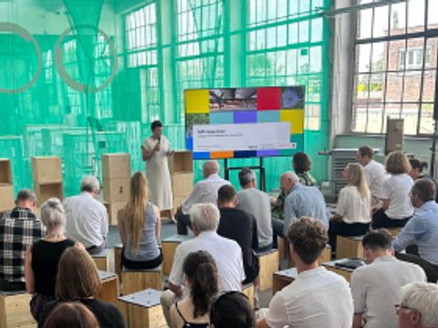 MPI Deep Dive Veranstaltung mit Fernseher im Hintergrund, auf dem eine Präsentation läuft