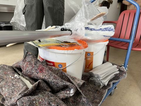 Materialien zum Malern unter anderem Farbe, Pinsel und Rollen