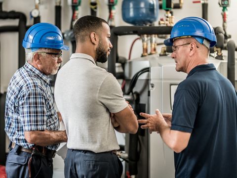 Facility-Manager erläutern einem Auszubildenden die Maschinen