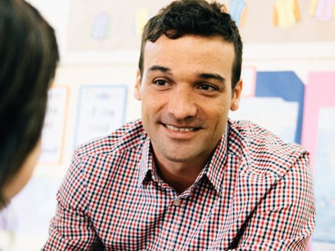 Ein Lehrer sitzt drei Schülerinnen gegenüber und spricht