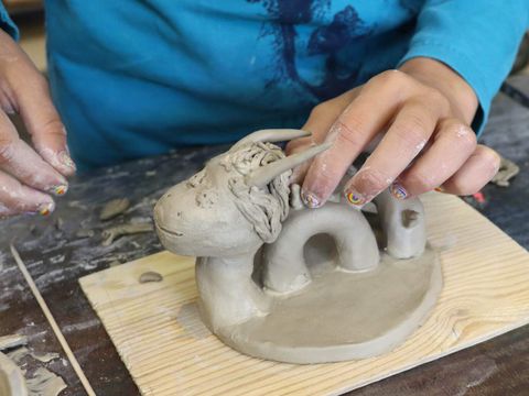 Kinderhänden modellieren einen kleinen Tondrachen