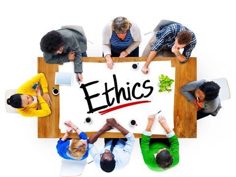 Eine Multiethnische Gruppe von Menschen sitzt an einem Tisch und diskutiert über Ethik.