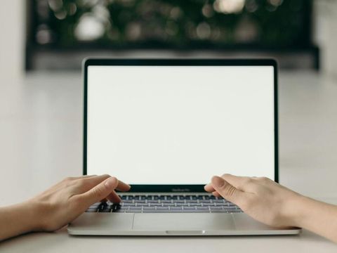Laptop mit Händen im Hintergrund ein Fenster
