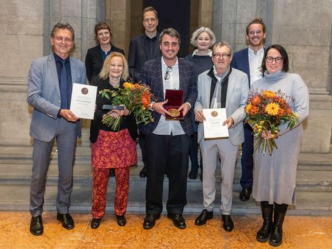 Martina Abri (1.Reihe, 2.v.l.) und Manuel Schottmüller (1.Reihe, Mitte) gemeinsam mit Senator Christian Gaebler, Landeskonservator Christoph Rauhut, Vertreter:innen der Hanna gGmbH und den Laudator:innen