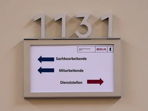 Ein Schild mit abgehenden Pfeilen von Sachbearbeitende, Mitarbeitende und Dienststellen an einer Tür