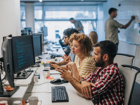 (M) Large group of computer programmers working in the office.