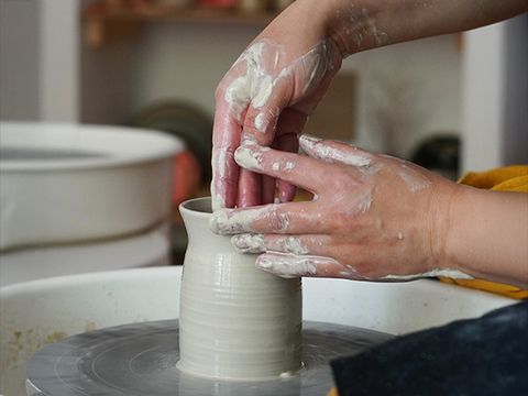 Eine Person töpfert eine Vase auf einer Drehscheibe