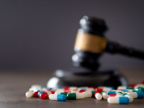 Tabletten liegen vor einem Richterhammer auf dem Tisch