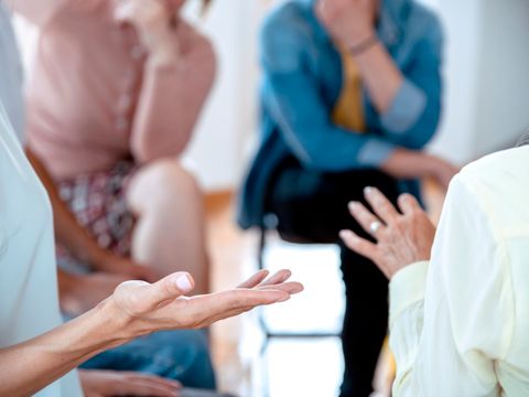 Menschen sitzen im Kreis auf Stühlen und unterhalten sich