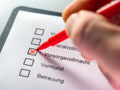 Eine Person kreuzt auf einer Liste Vorsorgevollmacht an.