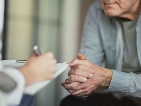 Person spricht mit einem Patienten und macht sich Notizen
