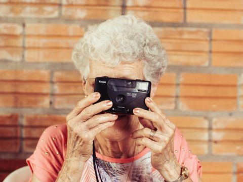 Eine ältere Frau macht ein Foto vom gegenüberstehenden Fotografen.