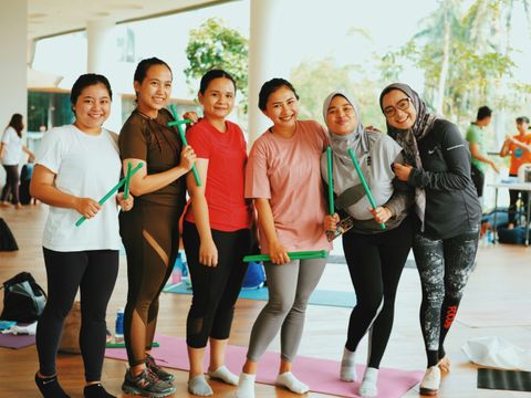 Eine Gruppe von Frauen steht zusammen in einem Sportraum und alle lächeln freundich in die Kamera.
