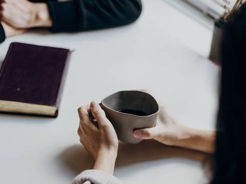 Frau mit Kaffeetasse und Frau mit Buch ohne Gesichter
