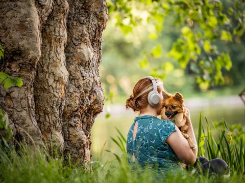 Frau mit Kopfhörern und Hund im Park