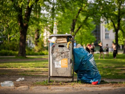 Müll neben vollem Mülleimer im Park