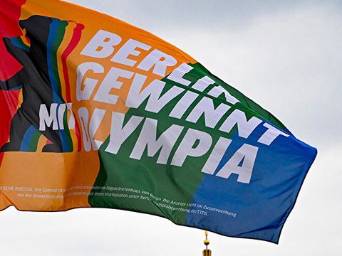 Foto von einer bunten Fahne. Darauf steht: Berlin gewinnt mit Olympia.