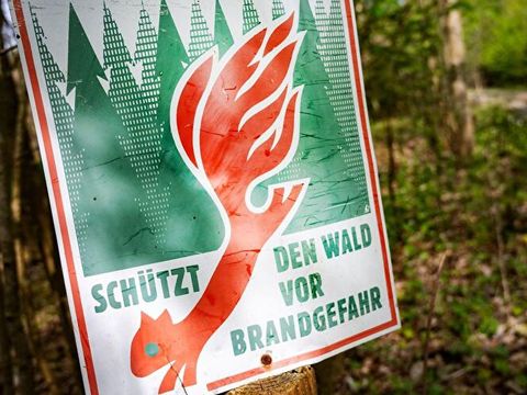 Schild im Wald mit Warnung vor Wald-Brand