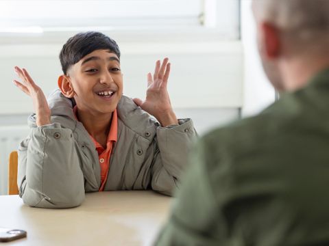 Junge sitzt Erwachsenem gegenüber und regt sich sichtlich auf