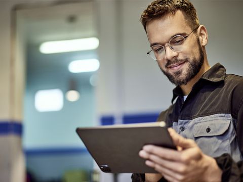 Werkstattleitung - Mann in Arbeitskleidung schaut auf ein Tablet