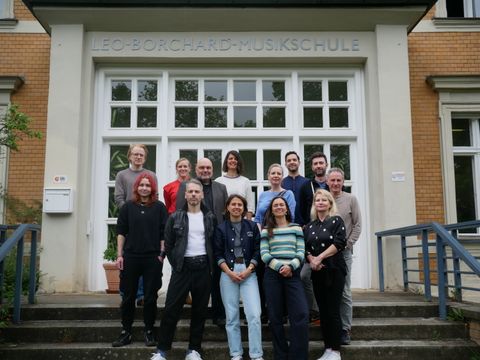 Das Team der Musikschule steht auf einer Treppe