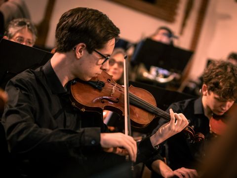Junger Mann spielt Violine im Orchester
