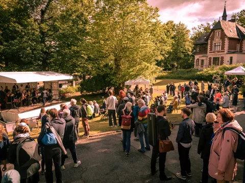 Viele Menschen vor einer Bühne im Garten beim Jubiläumsfest der Leo-Borchard-Musikschule