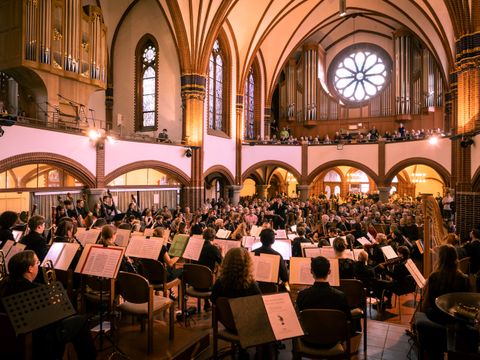 Ein Orchester vor einem großen Publikum in der Pauluskirche Zehlendorf.