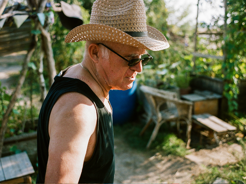 Ein Mann mit Sonnenhut und Sonnenbrille ist bei einem Arbeitseinsatz im Gemeinschaftsgarten.
