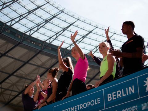 Fans und Sportlerinnen und Sportler jubeln im Stadion