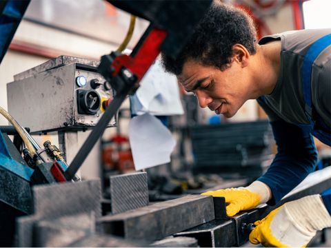Arbeiter bedient in einer Werkstatt eine Maschine