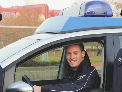 Zwei Auszubildende vor einem Streifenwagen