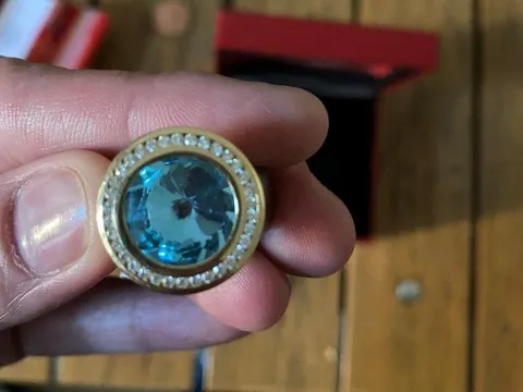 Goldfarbener Ring, hellblaue Steine, in schwarz-roter Schatulle