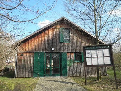 Eingangsbereich mit Gebäude aus Holz und Hinweisschild
