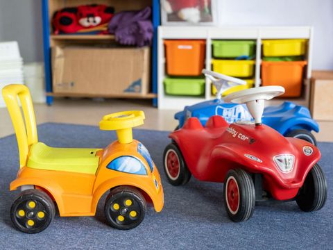 Drei Bobbycars stehen in einem Kita-Raum.