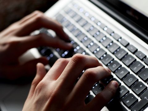 Zwei Hände, die auf einer Laptop-Tastatur tippen