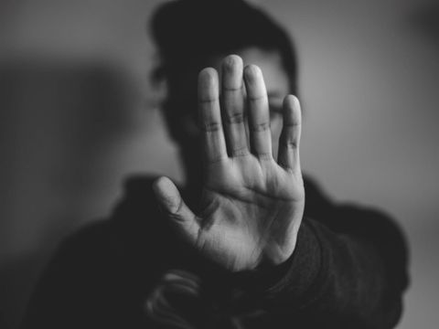 Eine weibliche Person signalisiert durch offene Handfläche am ausgestrecktem Arm "Halt, beziehungsweise Stop!"