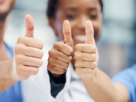 Pflegefachkräfte zeigen mit dem Daumen nach oben.