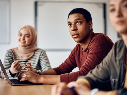 Multiethnische Gruppe Studenten sitzt zuhörend an einem Arbeitstisch