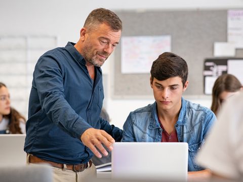 Lehrer unterstützt Schüler am Computer