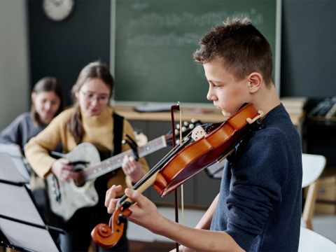 Mehrere Kinder spielen in einem Schul-Musikraum Instrumente