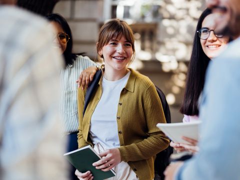 Mehrere freudige Studierende unterhalten sich im Freien