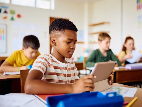 Schüler sitzt im Klassenzimmer und arbeitet an einem Tablet