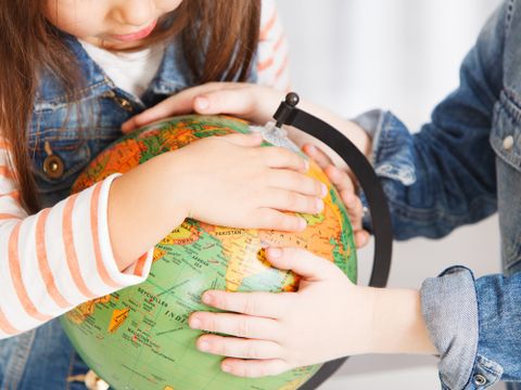 Kind hält kleinen Globus mit beiden Händen fest