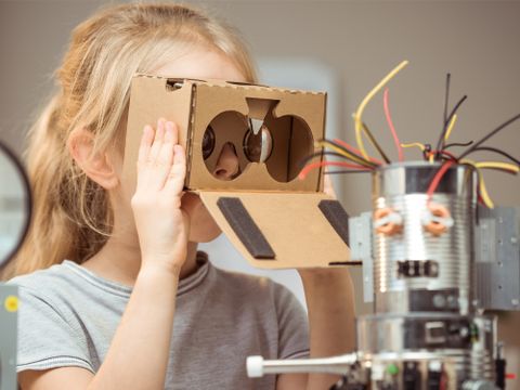 Mädchen guckt sich mit selbstgebauter Lupenbrille einen selbstgebauten Roboter an