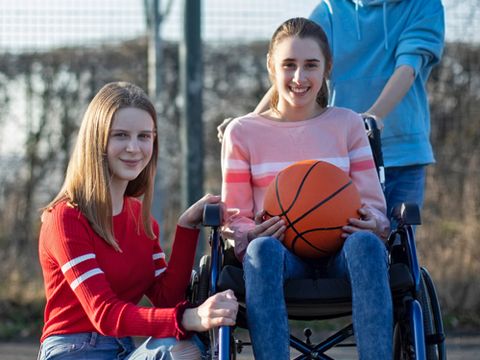Mädchen im Rollstuhl mit zwei Freunden