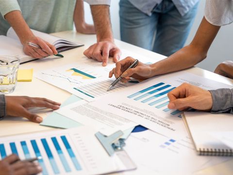 Gruppe von Mitarbeitern arbeitet an einem Finanzplan, Bildausschnit nur auf den Tisch und die Hände