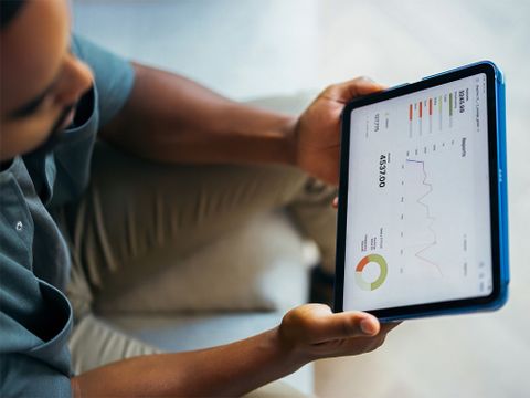 Person hält Tablet mit abgebildeten Statistiken in der Hand