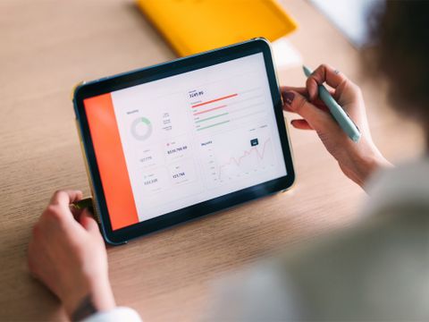 Statistiken werden auf Tablet angezeit, welches auf einem Tisch steht und von Person bedient wird